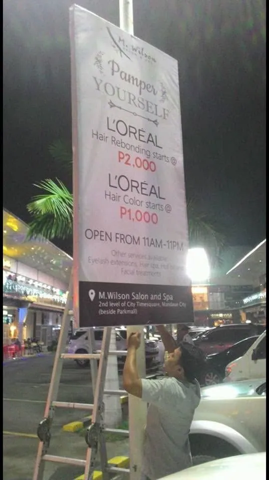 MCAV crew installing a M. Wilson Salon and Spa framed tarpaulin at City Time Square, Mandaue City