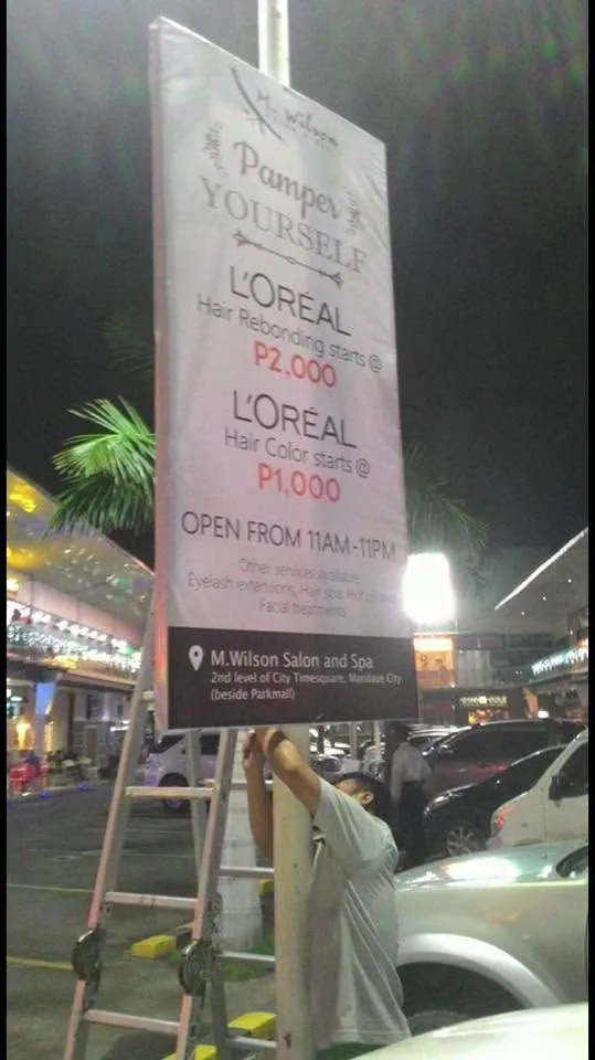MCAV crew installing a M. Wilson Salon and Spa framed tarpaulin at City Time Square, Mandaue City